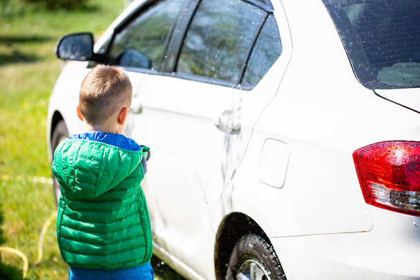 Söpö poika pesee autoa ulkona
 - Valokuva, kuva