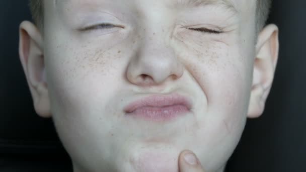 Zamyšlenou tváři modrýma očima dospívajícího chlapce s pihy zblízka - Záběry, video