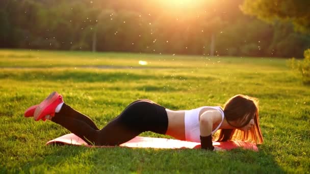 Push up nebo tisk zvýší výkon mladá žena. Dívka na trávu crossfit silový trénink v záři ranního slunce proti bílé obloze s copyspace. Kavkazská model. - Záběry, video