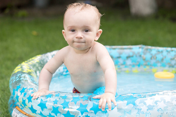 Ritratto di bambino carino di 10 mesi che si gode il nuoto nella piscina gonfiabile
 - Foto, immagini
