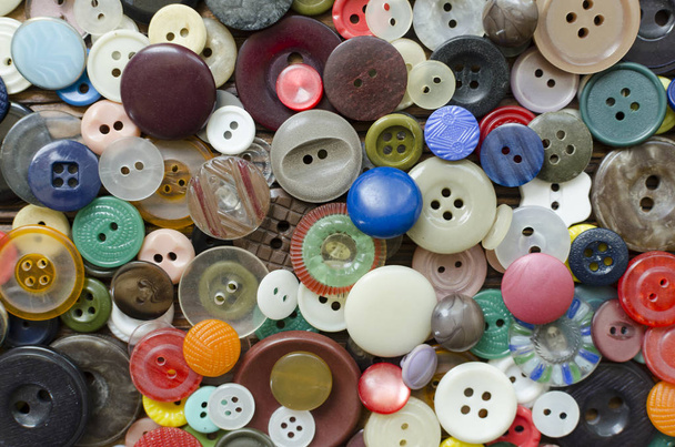 Colored plastic buttons on brown wooden background - Фото, изображение