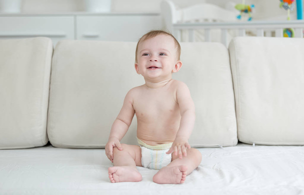 Cheerful smiling baby boy sitting on sofa at living room - Photo, Image