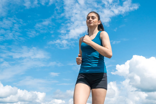 Молода спортивна дівчина біжить на тлі блакитного неба
 - Фото, зображення