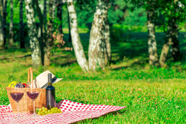 due bicchieri di vino rosso e un cestino da picnic con frutta su un tavolo
 - Foto, immagini
