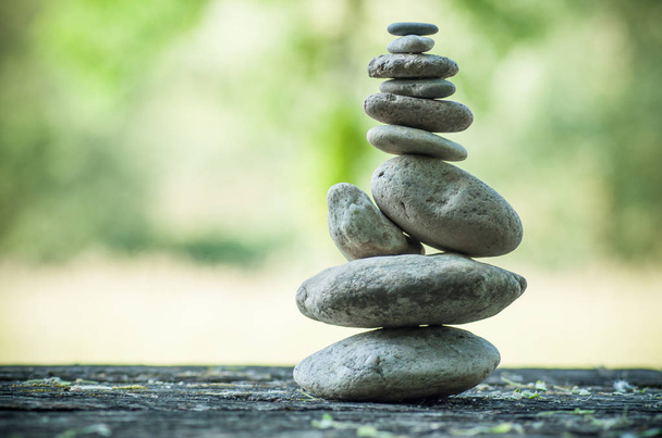  stones balance on wooden table on green blurred background - Foto, Imagen