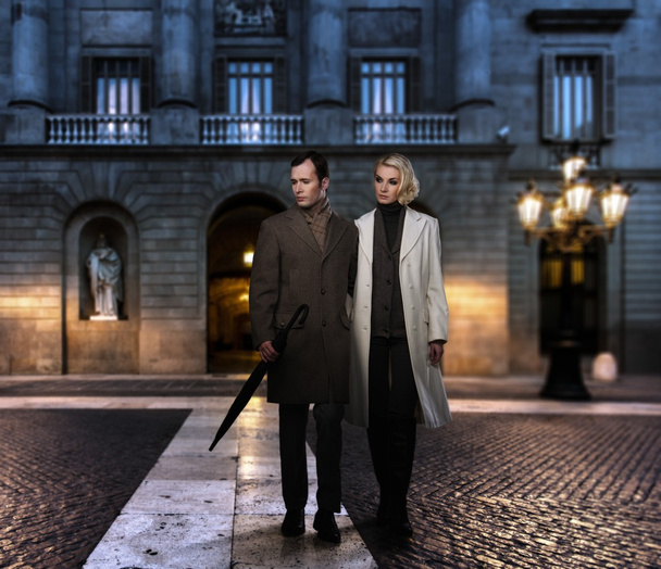 Couple élégant en manteaux contre la façade du bâtiment en soirée
 - Photo, image