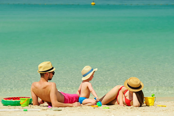Sahilde bir aile. İki yaşında bir çocuk plajda anne ve babasıyla plaj oyuncaklarıyla oynuyor.. - Fotoğraf, Görsel