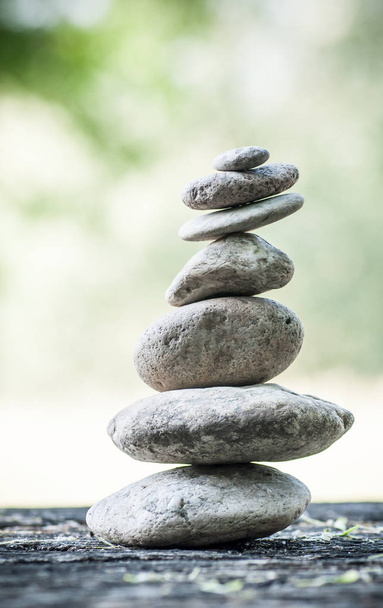  stones balance on wooden table on green blurred backg - Fotografie, Obrázek