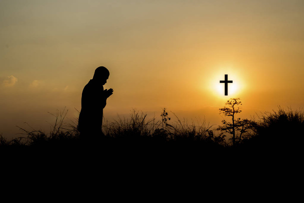 Silhouette man praying in front of cross with faith and belief - Photo, Image