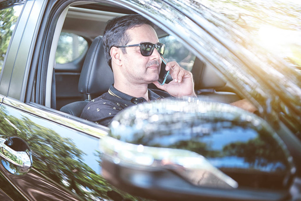 pakistani muslim Man водить машину і розмовляє по мобільному телефону, концентруючись на дорозі - Фото, зображення
