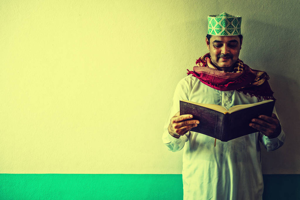 Dindar Müslüman adam ayakta ve ecek içinde Kur'an okuma - Fotoğraf, Görsel