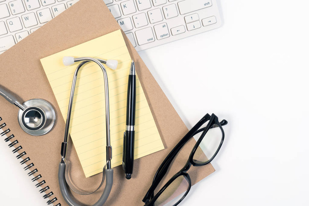 Close up of stethoscope, paper note, notebook, glasses, pen and on calendar for doctor appointment. Doctor appointment plan concept. - 写真・画像