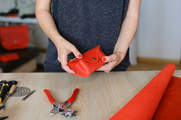 Европейская женщина делает красный кожаный бумажник в ателье
. - Фото, изображение