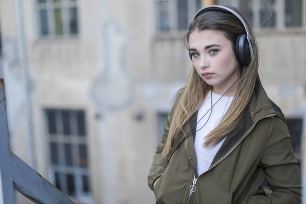Teen posing listening to music wearing headphones - Fotó, kép