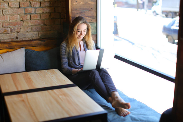Glad girl sitting near of coffee and notebook in luncheonette. - Фото, зображення