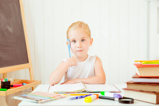 muotokuva huomaavainen pieni tyttö näköinen ymmällään tehdessään kotitehtäviä kotona
 - Valokuva, kuva