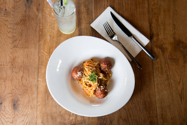 Top view of spaghetti pasta with meatballs and tomato sauce on wooden table - Foto, immagini