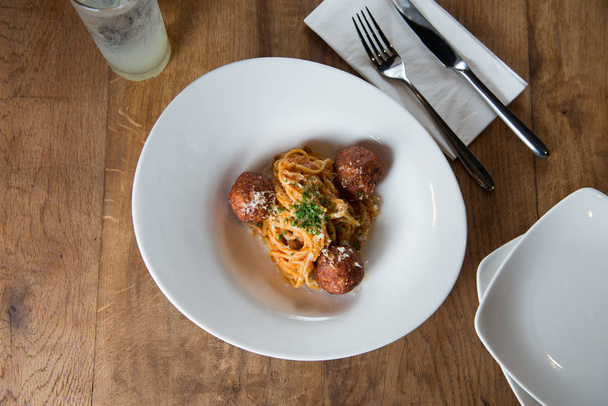 Top view of spaghetti pasta with meatballs and tomato sauce on wooden table - Foto, imagen