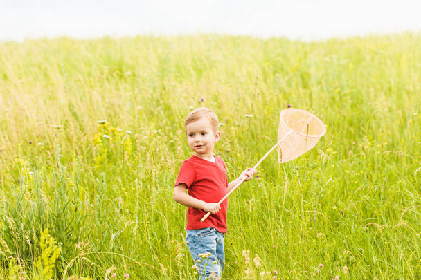 Little boy with a butterfly net on a summer meadow - Foto, imagen