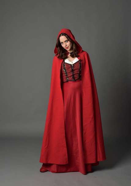retrato de comprimento total da senhora morena vestindo traje de fantasia vermelho com capa, em pé posar no fundo do estúdio cinza
. - Foto, Imagem