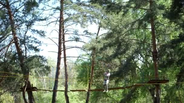 CHERKASA, UKRAINE-MAY 1, 2018: The visitors enjoy their treetop adventure, climbing on the wooden block hanging with the rope between tree to tree. outdoors sport activity - Felvétel, videó