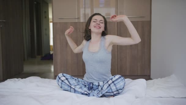 Smiling woman sitting on bed and stretching - Footage, Video