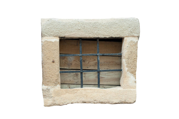 Небольшое каменное окошко с черными металлическими прутьями, изолированными на белом фоне. Винтажное окно
. - Фото, изображение