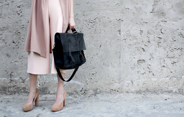 Κορίτσι στο ροζ look, με μαύρη δερμάτινη τσάντα, θέτουν σχετικά με το ιστορικό concrette. Μόδα και το κομψό έννοια. - Φωτογραφία, εικόνα