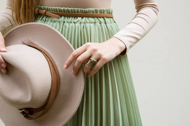 Шляпа, бежевая блузка и бирюзовые складки юбка на легкой улице backgraund. Мода и стильная концепция
. - Фото, изображение