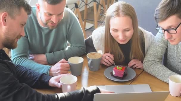 Szczęśliwy Grupa z przyjaciółmi lub współpracownikami, picia kawy i śmiejąc się i razem przy użyciu komputera w małej kawiarni lub winiarni - Materiał filmowy, wideo