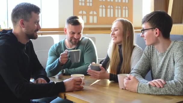 Ευτυχισμένη ομάδα από φίλους ή επαγγελματικούς συνεργάτες πίνοντας καφέ και γελώντας και χρησιμοποιώντας υπολογιστή μαζί σε ένα μικρό καφέ ή μπαρ κρασιού - Πλάνα, βίντεο