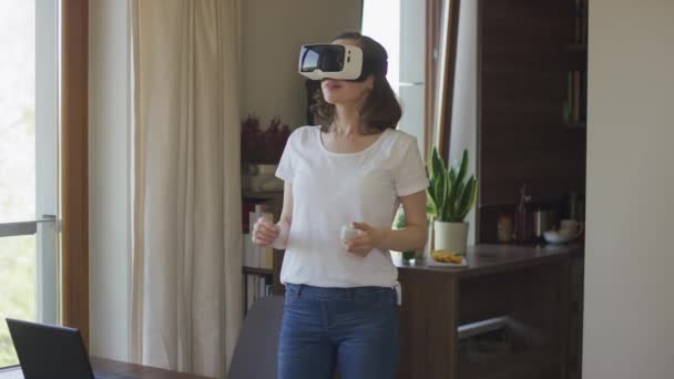 Mujer joven de pie en casa con auriculares VR
 - Metraje, vídeo