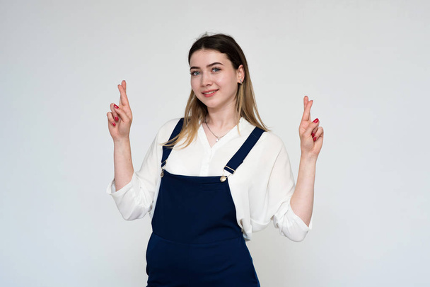 Portrait of a beautiful girl on a white background showing hands up with a smile. - Valokuva, kuva