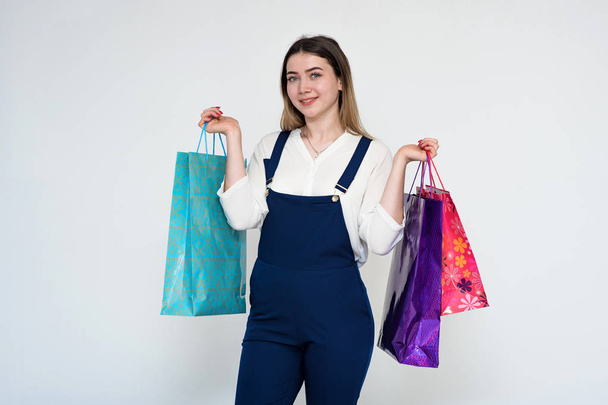 Portrait of a young beautiful girl on a white background holding packages from the store. - Valokuva, kuva
