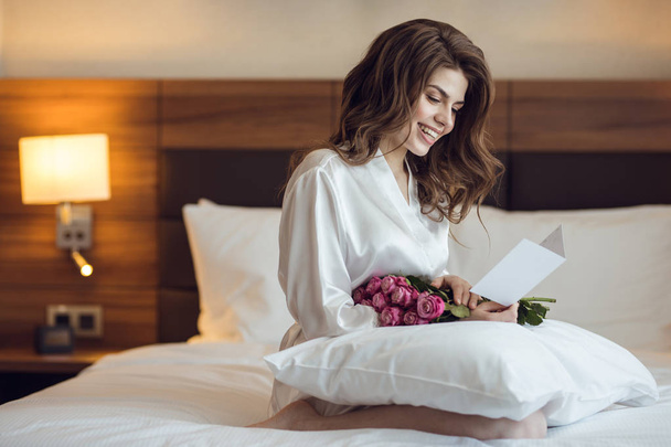 Lächelnde Frau mit Blumenstrauß im Hotel - Foto, Bild