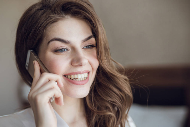 Hymyilevä kaunis tyttö puhuu puhelimessa
 - Valokuva, kuva