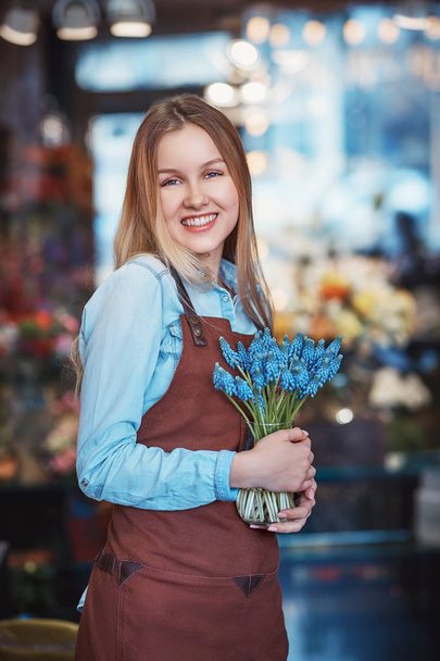 Menina feliz com flores azuis em uma loja
 - Foto, Imagem