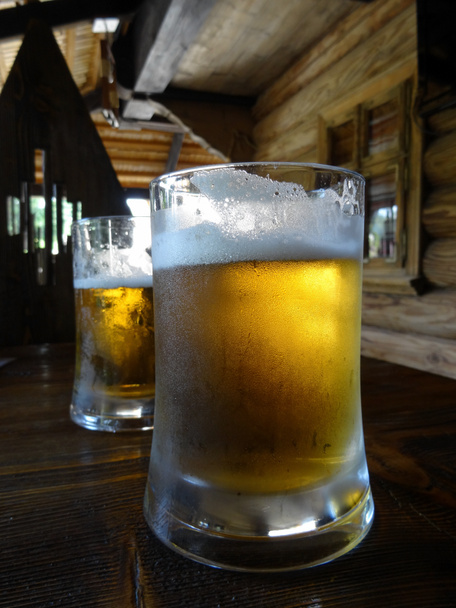 Zwei Pints Bier mit Schaum auf dem Glas auf dem Holztisch - Foto, Bild