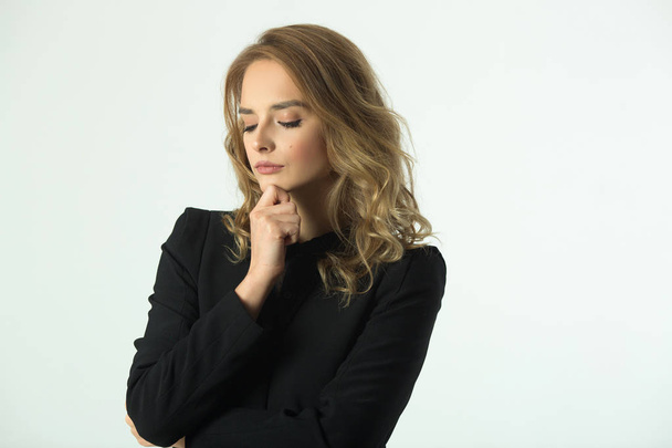 a strict beautiful young girl in a black jacket on a white background with a pensive look - Foto, immagini