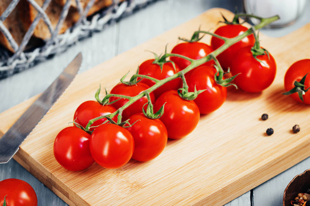 Branch of Cherry tomatoes on wooden board. Top view - Фото, изображение