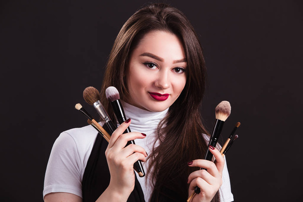 Makeup artist with brushes in hand on a black background - Fotoğraf, Görsel