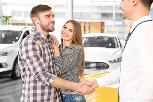 Young man shaking hands with salesman in car salon - Photo, Image