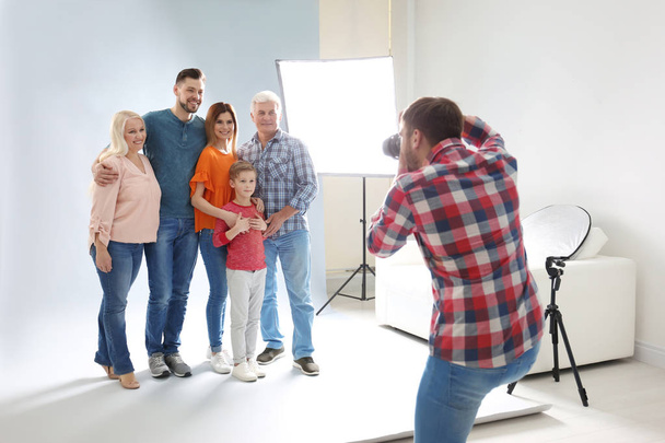 Professional photographer taking photo of family in studio - Фото, изображение