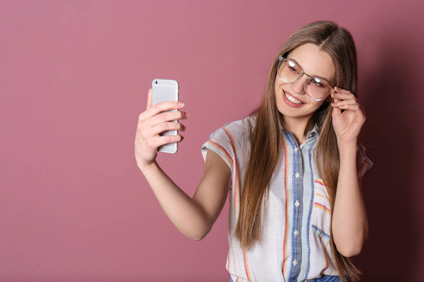 Young beautiful woman taking selfie against color background - Zdjęcie, obraz