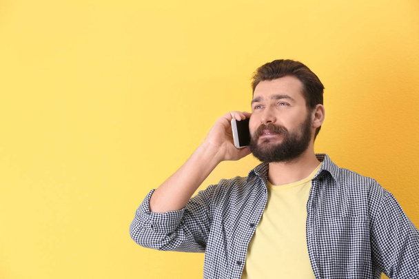 Portrait of confident mature man with mobile phone on color background - Photo, image