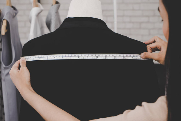 Стилист одежды измеряет заднее плечо пиджака
 - Фото, изображение