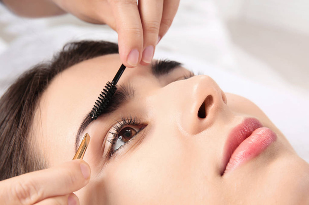 Young woman having professional eyebrow correction procedure in beauty salon, closeup - Foto, Imagem