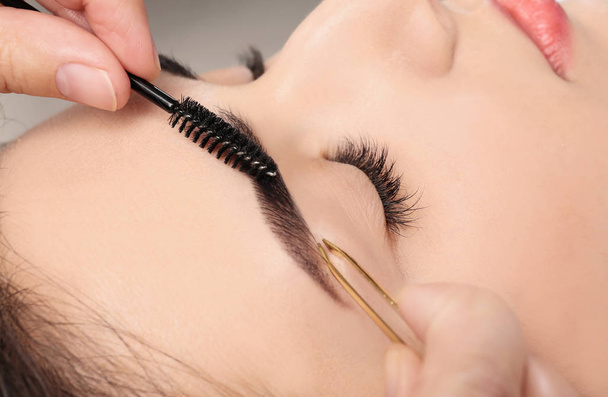 Young woman having professional eyebrow correction procedure, closeup - Foto, Imagem