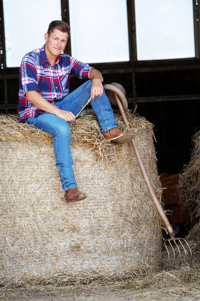 blond man in jeans sitting on haystack - Foto, imagen