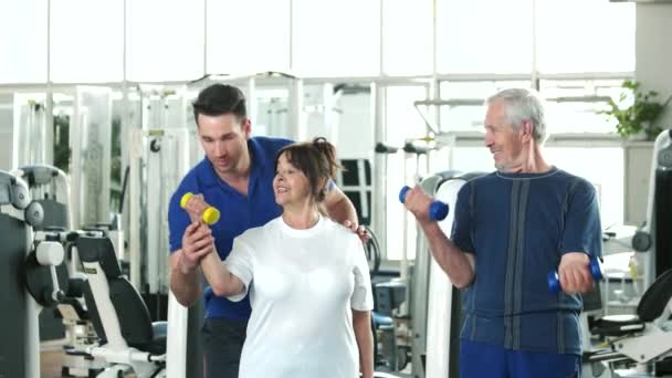Személyi edző segít, emelje fel a súlyzók idősek. - Felvétel, videó